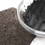 Picture of raw fresh black Amazon Forest Black Clay with bowl of wet clay for facial mask.