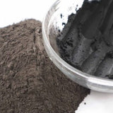 Picture of raw fresh black Amazon Forest Black Clay with bowl of wet clay for facial mask.