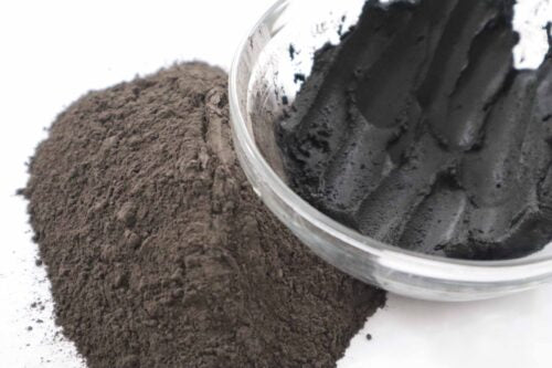 Picture of raw fresh black Amazon Forest Black Clay with bowl of wet clay for facial mask.