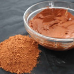 Picture of raw fresh red Amazon Forest Red Clay with bowl of wet clay for facial mask.